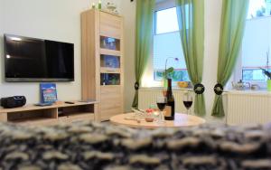 a living room with a tv and a table with wine glasses at Ferienwohnung ADMIRAL in Kühlungsborn