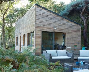 une petite maison avec 2 chaises et une terrasse dans l'établissement Au courtil des chênes marins, meublé 3 étoiles, à Digosville