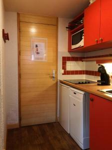 eine Küche mit roten Schränken und einer Tür in der Unterkunft Résidence DIGITALE, Le Lauze Plagne 1800 in Plagne 1800