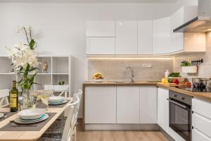 a kitchen with white cabinets and a table at New Cosy Apartment Ivan in Opatija