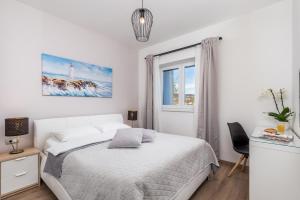 a white bedroom with a bed and a window at New Cosy Apartment Ivan in Opatija