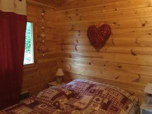 Dormitorio de una cabaña de madera con un corazón en la pared en Chalet le val’tin, en Ventron
