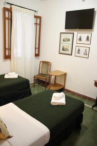 a room with two beds and a chair and a tv at Lago Hotel in Villa Rumipal