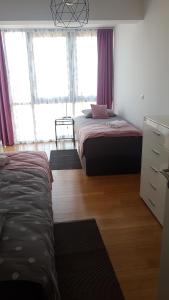 1 Schlafzimmer mit 2 Betten und Fenstern mit lila Vorhängen in der Unterkunft Penthouse HEART OF SLAVONIA **** in Ðakovo