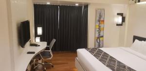 a bedroom with a bed and a desk with a television at Hotel surya dev residency in Bangalore