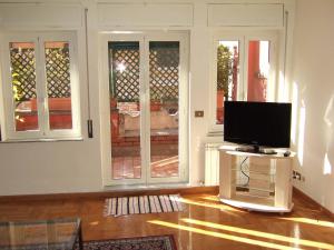 sala de estar con TV en un soporte frente a las ventanas en Flavia Rooftop Apartments, en Roma