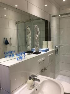 een badkamer met een wastafel en een spiegel bij Fewo Schröder - BUDE 63a - mit Strandkorb am Meer in Westerdeichstrich