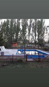 a swimming pool in a park with a fence at Complejo Los Parrales in General Alvear