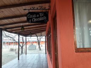 a sign on the side of a red building at Complejo Los Parrales in General Alvear