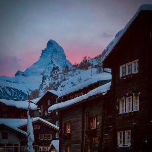 a mountain in the distance with buildings and snow at Kirchplatz Apartment Lupus in Zermatt