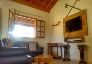 a living room with a couch and a tv at Chalé Boa Vista in São Thomé das Letras