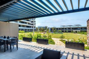 un patio avec une table et des chaises et un bâtiment dans l'établissement Pebble Beach 128 Umdloti Durban, à Umdloti