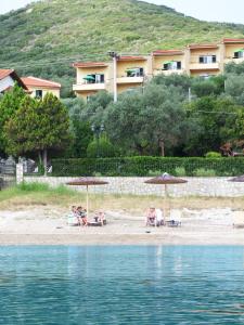 un grupo de personas sentadas en una playa con sombrillas en The Yellow Houses, en Agios Nikolaos