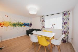 a dining room with a white table and yellow chairs at River Court Apartments by Paymán Club in Cambridge