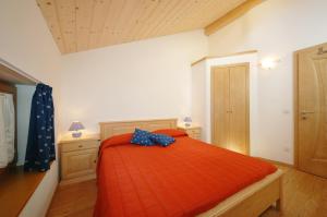 - une chambre avec un lit et une couette en orange dans l'établissement Casa Seler - Appartamento verde, à Predazzo