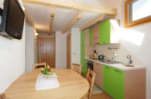 Il comprend une cuisine et une salle à manger avec une table en bois. dans l'établissement Casa Seler - Appartamento verde, à Predazzo