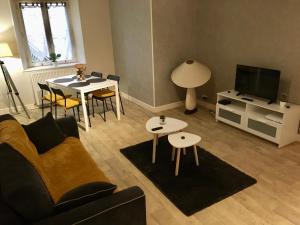 Appartement Guéret في غويريت: غرفة معيشة مع أريكة وطاولات وتلفزيون