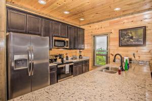 a kitchen with a stainless steel refrigerator and wooden walls at Rainwater Falls in Gatlinburg