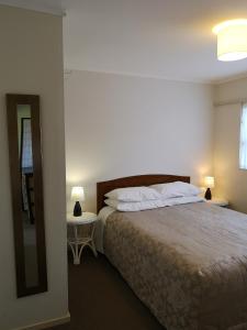 1 dormitorio con 1 cama con 2 lámparas y espejo en Opua Boutique Seaview Motel en Opua