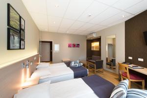 a hotel room with three beds and a desk at Hôtel de l'Univers Liège in Liège