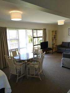 - un salon avec une table, des chaises et un canapé dans l'établissement Opua Boutique Seaview Motel, à Opua