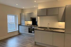 a kitchen with white cabinets and a large window at The Warren @ Short Stays in Basingstoke