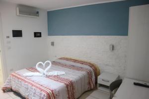 una camera da letto con un letto e due asciugamani di torquemada beach club a Margherita di Savoia