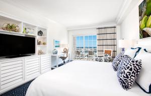 a white bedroom with a large bed and a flat screen tv at Oceans Edge Key West in Key West
