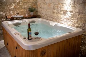 a bath tub with a bottle of wine and a glass at Apanemia Inn Studio in Lofou