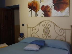 1 dormitorio con 1 cama con sábanas azules y una pintura en B&B Il Campo dei Papaveri, en Mornese