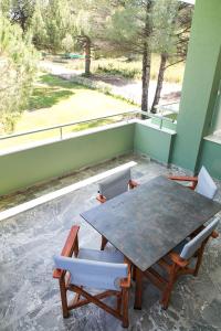a table and chairs on a balcony with a view of a field at Alexandros Hotel Apartments in Vourvourou