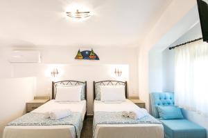 a bedroom with two beds and a blue chair at Alexandros Hotel Apartments in Vourvourou