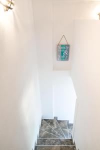 a staircase in a white room with a clock on the wall at Alexandros Hotel Apartments in Vourvourou