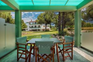 a patio with a table and chairs and a house at Alexandros Hotel Apartments in Vourvourou