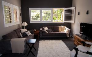 a living room with a couch and a tv at Mooring Lane Lodge in Whitianga