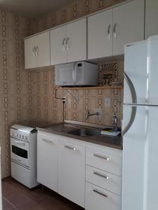 cocina con armarios blancos y nevera blanca en Excelente localização! Perto da praia com estacionamento, ar condicionado, wi-fi e Netflix!, en Balneário Camboriú