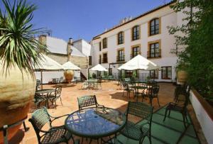 a patio with tables and chairs and a building at Hotel Rosaleda Don Pedro in Úbeda