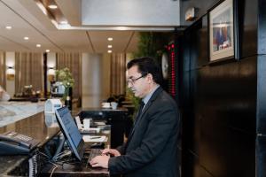 um homem em pé na frente de uma secretária com um laptop em Diwan Casablanca Hotel & Spa em Casablanca