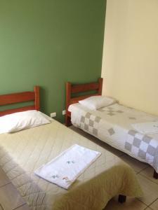 two beds in a room with green walls at HOTEL CENTRAL in Juruaia