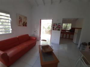 a living room with a red couch and a table at Chez JUJU in Le Gosier