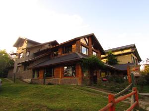 uma grande casa de madeira com uma cerca em frente em La Roca de la Patagonia em Villa La Angostura