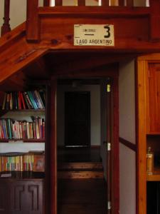 una puerta abierta a una biblioteca con una estantería de libros en La Roca de la Patagonia en Villa La Angostura