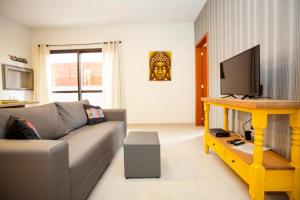 a living room with a couch and a flat screen tv at Barra Holiday Apartamentos in Florianópolis