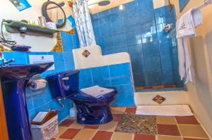 a blue bathroom with a toilet and a sink at Casa del Lago Lodging House in Puerto Ayora