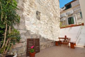 een patio met een tafel en een stenen muur bij Apartment Irvin - sweet apartment in Trogir