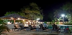 a pool at night with chairs and an umbrella at Pousada Recanto dos Passaros in Balsas