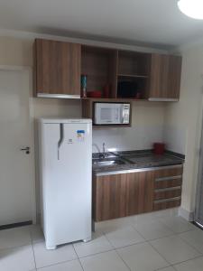 a kitchen with a white refrigerator and a microwave at Thermas Lacqua Diroma Caldas Novas in Caldas Novas