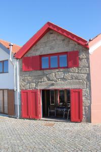 um edifício com portas vermelhas e um telhado vermelho em Casa do Mar em Vila Chã