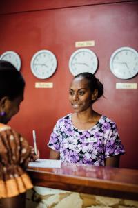 eine Frau, die an einem Schreibtisch in einem Zimmer mit Uhren sitzt in der Unterkunft Kaiviti Motel in Port Vila