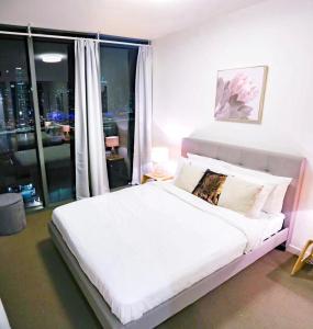 a white bed in a room with a large window at Lucid Apartment South Brisbane in Brisbane